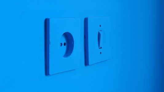 two light switches on a blue wall.