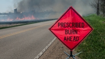 a prescribed burn road sign with smoke in the distance