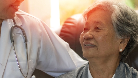 an older woman smiling next to a person wearing a medical coat an stethoscope