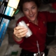 In the ISS, a woman demonstrates water recycling by holding a can.